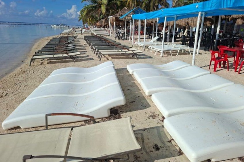 A beach with lounge chairs and umbrellas. 5