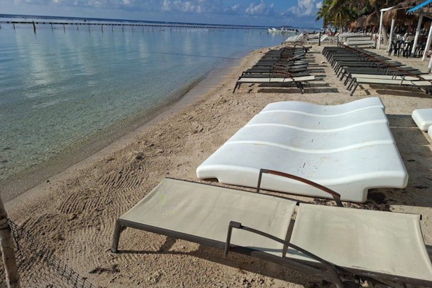 A beach with lounge chairs and a pier in the background. 4