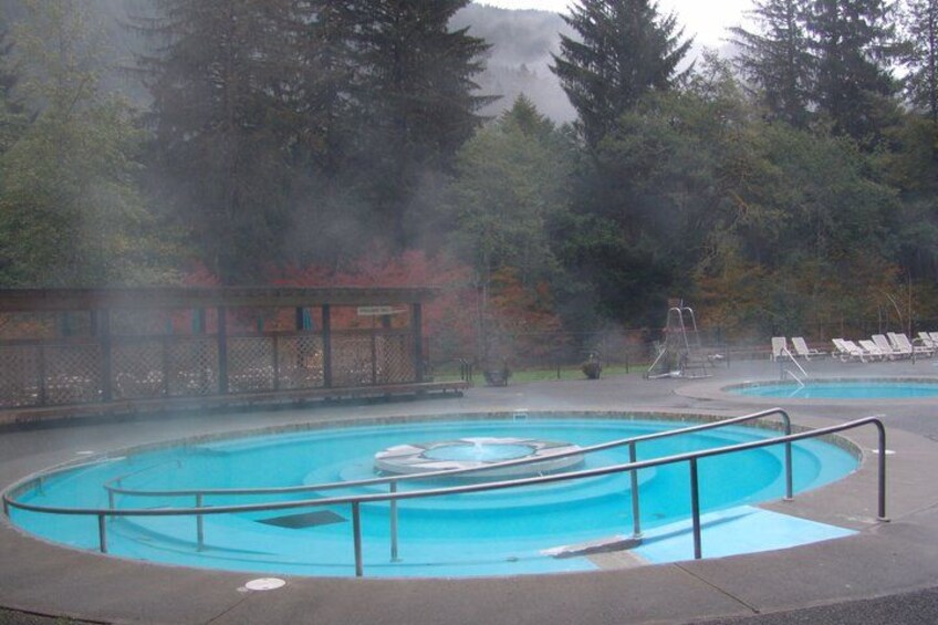 A hot spring pool with a wooden deck and lounge chairs. 2