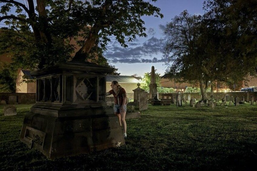A cemetery with gravestones, a gazebo, and a person standing near the gazebo. 1