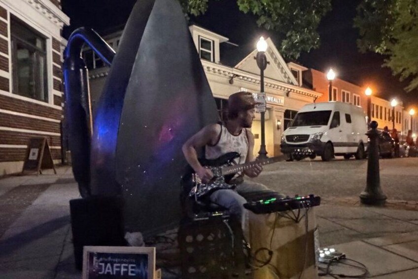 A person playing a musical instrument on a street at night. 2