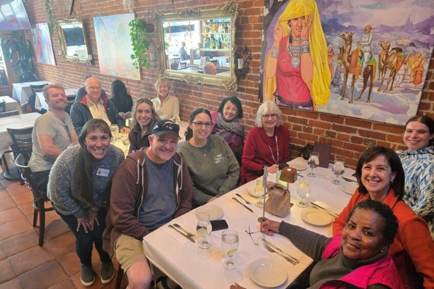 A group of people seated at a table in a restaurant with a mural on the wall. 4