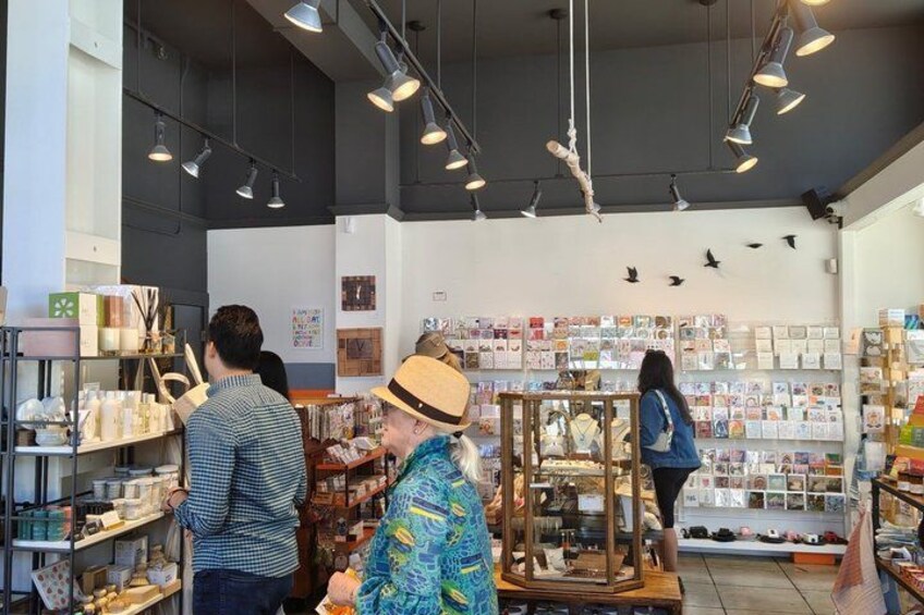 A store interior with shelves of products, a display case, and hanging lights. 3