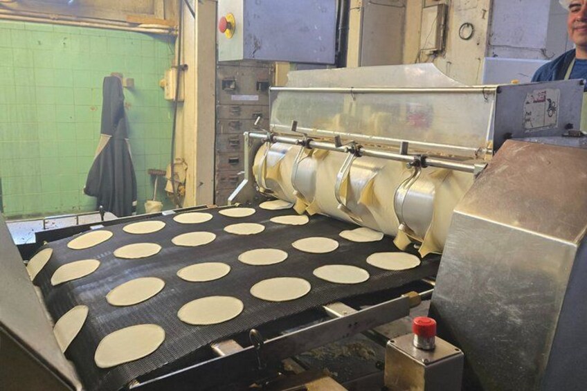 A doughnut-making machine with a conveyor belt and circular molds. 5