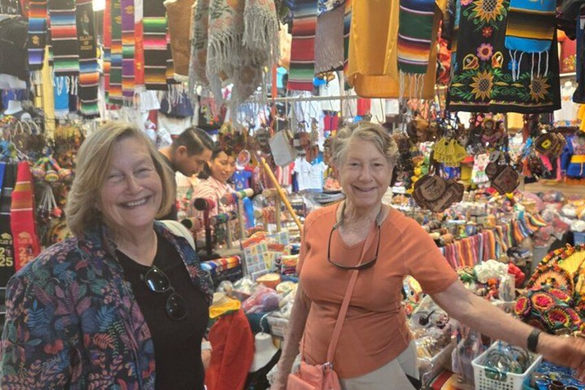 Two people in a market with colorful textiles and crafts. 4