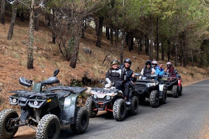 A group of people on ATVs on a forested road. 1