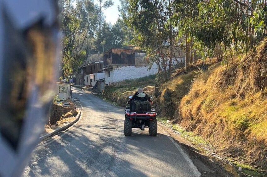 A quad bike on a narrow road with houses on the side. 5