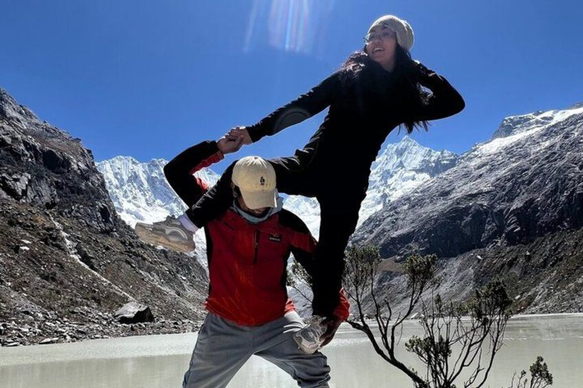 Two people in a mountainous area with a lake and snow-capped peaks in the background. 4