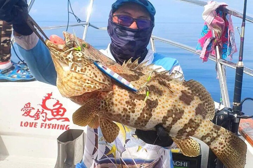 A person holding a large fish with a fishing rod. 4