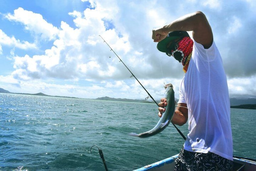 A person on a boat holding a fish, with a body of water and distant mountains in the background. 3