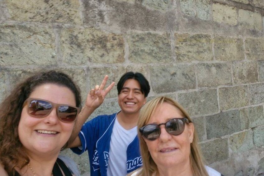 Three people posing in front of a stone wall. 4