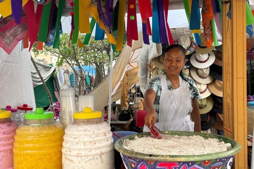 A person preparing food at a stall with colorful decorations and various containers. 1