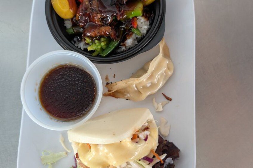 A meal with a bowl of rice, vegetables, and meat, a sandwich with cheese, and a small bowl of sauce. 1