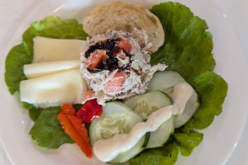 A salad with lettuce, cucumber slices, a bread roll, and a creamy dressing. 4