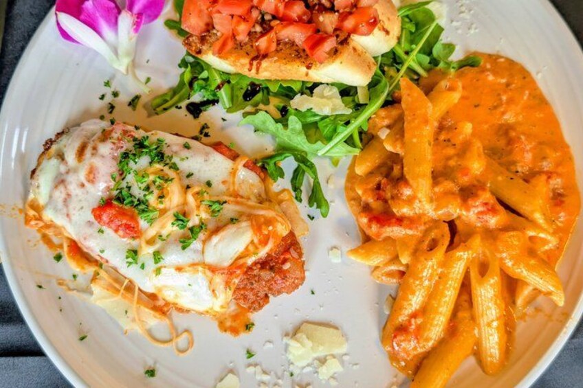 A plate with a chicken breast, pasta, and fries. 2