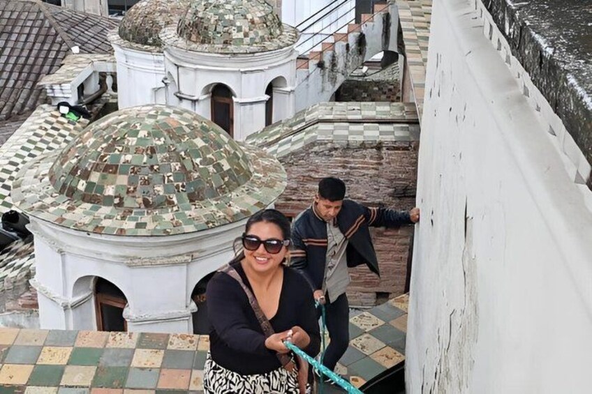 A person standing on a rooftop with a view of domed buildings and a white wall. 3