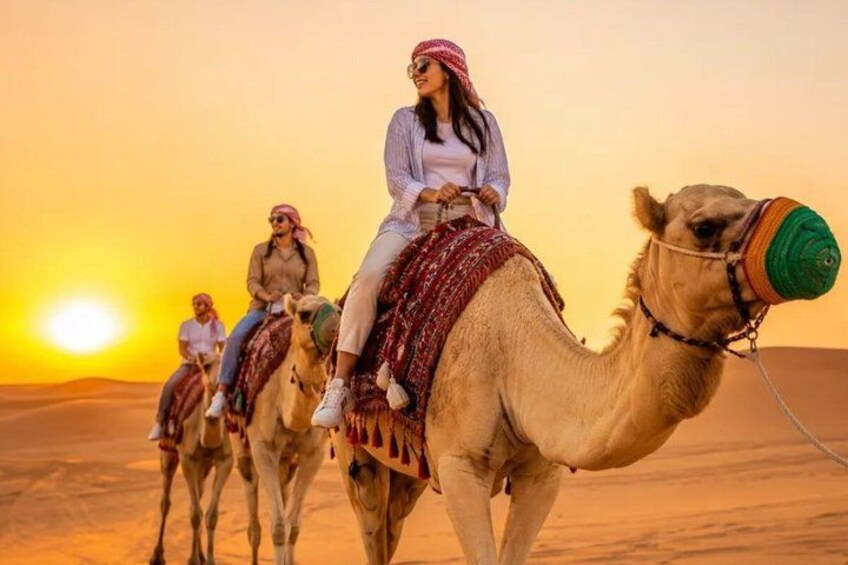 A camel caravan in a desert landscape with the sun setting in the background. 5