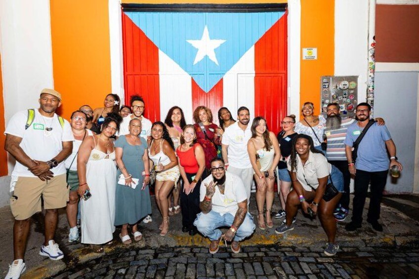 A group of people posing in front of a building with a flag. 1