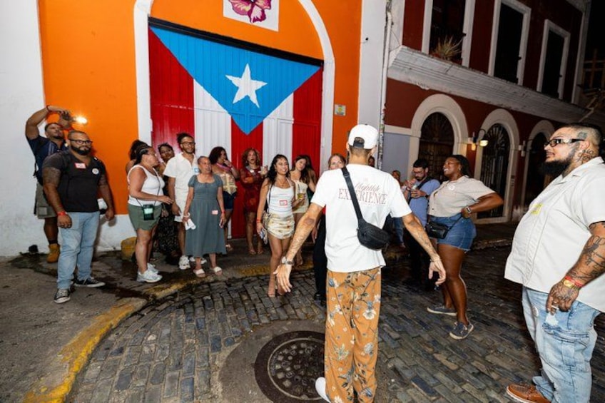 A group of people standing in front of a building with a Puerto Rican flag. 2