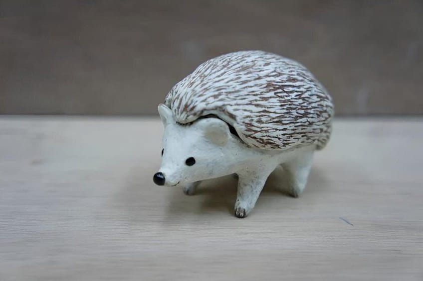 A small hedgehog figurine on a wooden surface. 2