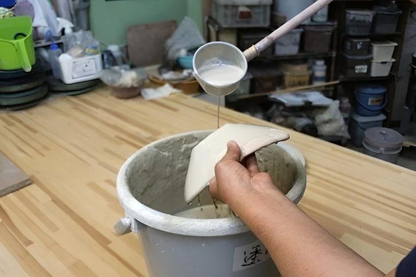 A person pouring a white liquid from a small container into a bucket. 5