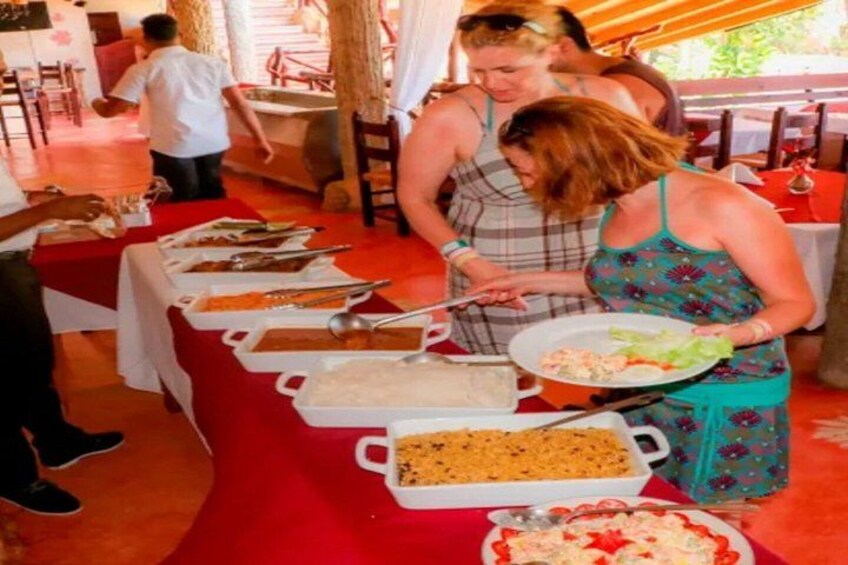 A buffet table with various dishes and a person serving food. 2