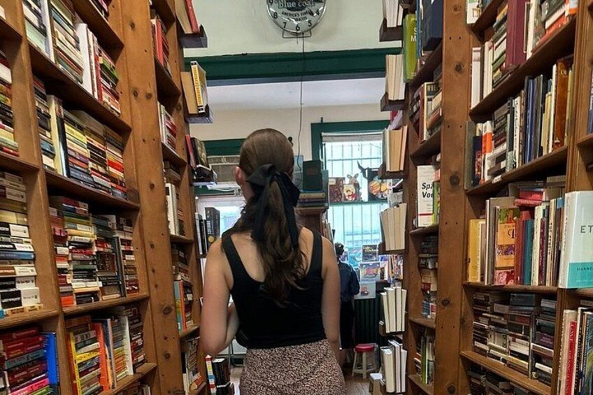 A person walking through a library aisle with bookshelves on either side. 1