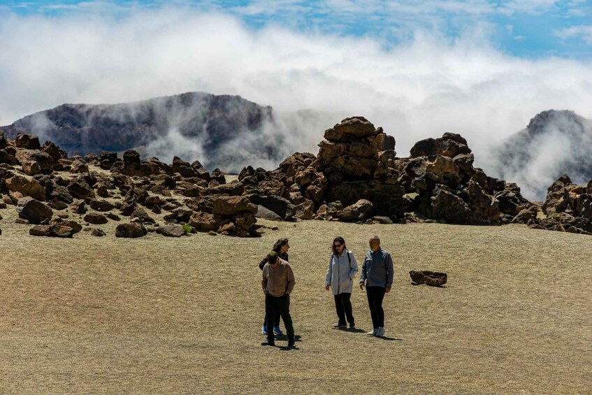 Un groupe de personnes marchant sur un terrain rocailleux, avec des montagnes en arrière-plan. 1