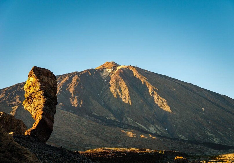 Une montagne avec une formation rocheuse imposante au premier plan et un ciel dégagé. 5
