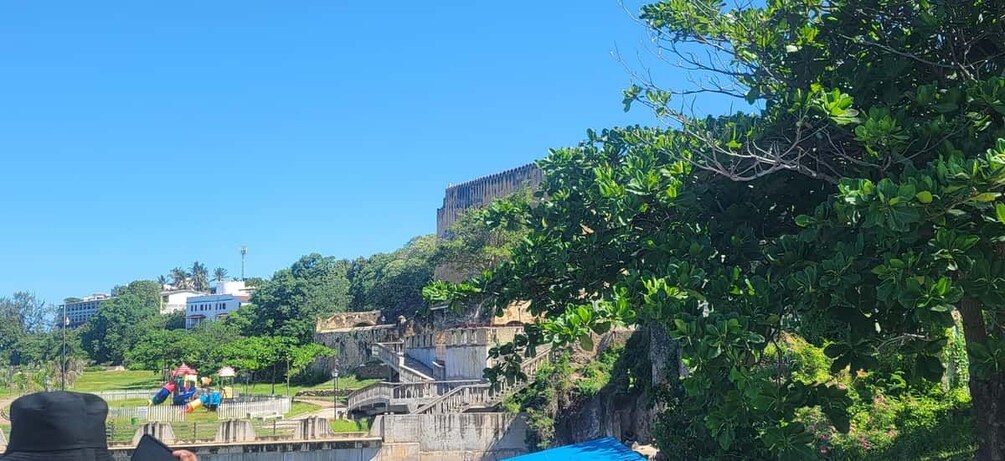A park with a playground, a bridge, and a large building on a hill. 5