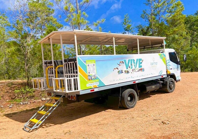 A mobile home with a covered porch, parked on a dirt ground with trees in the background. 4