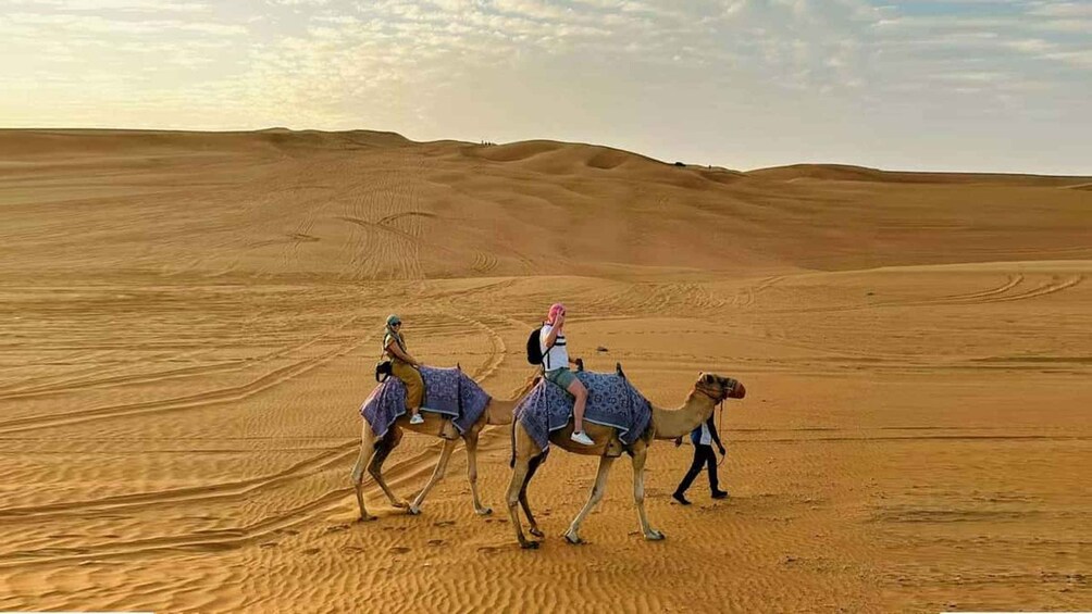 Un paysage désertique avec des dunes de sable et une caravane de chameaux. 4