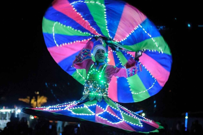 Une personne qui se produit sur scène en utilisant une grande roue lumineuse en rotation. 2