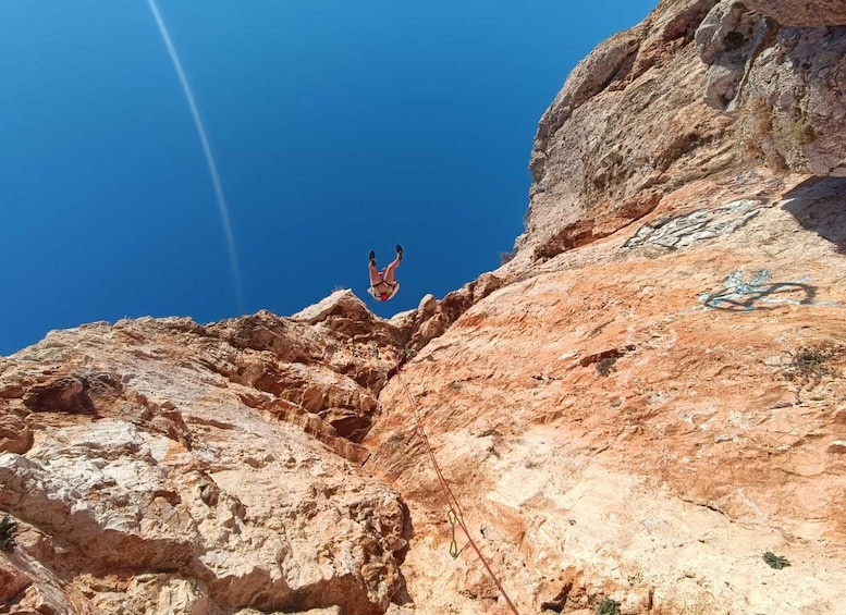 Una persona haciendo bungee jumping desde un acantilado rocoso con un cielo azul despejado al fondo. 1