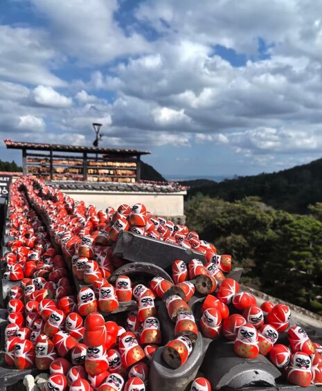 A large number of red and white painted wooden figures arranged in rows on a rooftop. 4