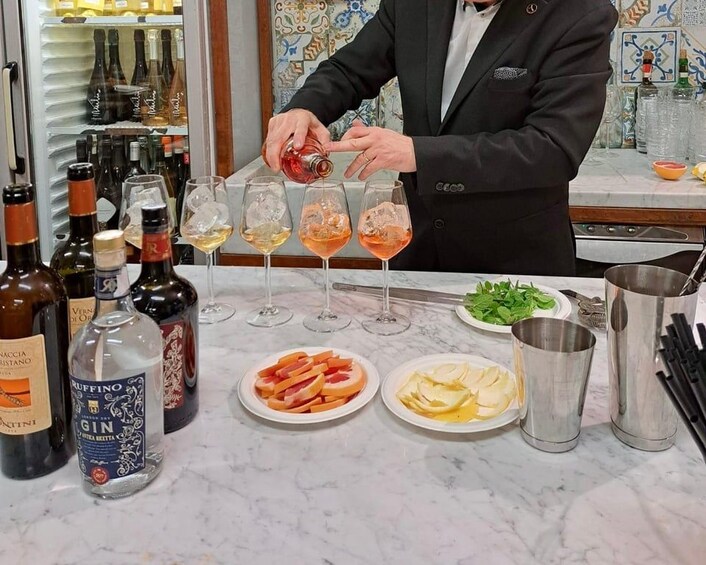 A bartender pouring a drink into a glass, with bottles and plates of food on the counter. 4