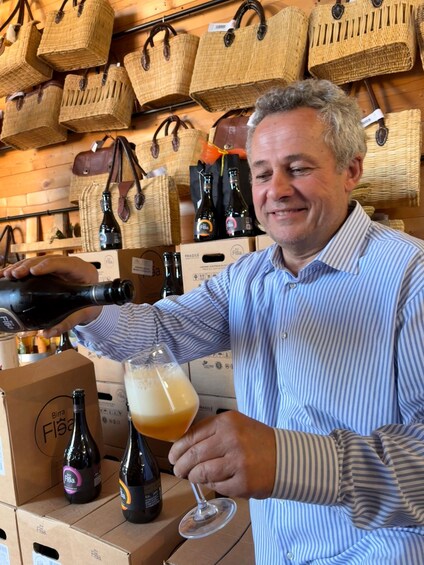 A person pouring a drink into a glass. There are boxes and bottles in the background. 2