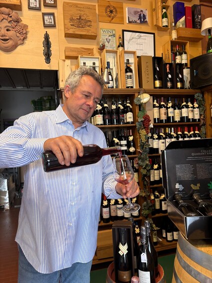 A man pouring wine into a glass in a wine shop. 5
