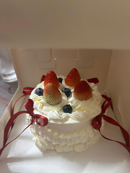 Un gâteau à la crème fouettée, aux fraises et aux myrtilles, décoré de rubans rouges. 5