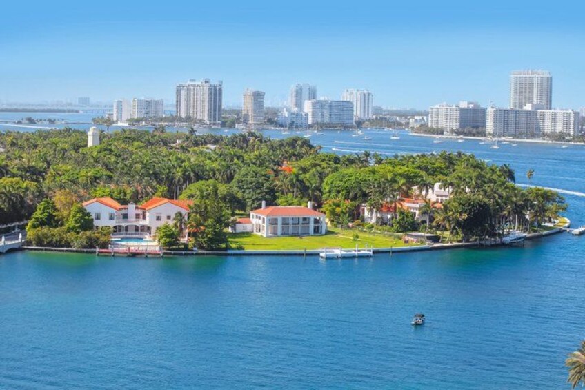 A coastal cityscape with a marina, residential buildings, and a dense tree line. 5