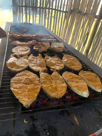 Un barbecue avec différentes sortes de viandes et de poissons en train de cuire. 3