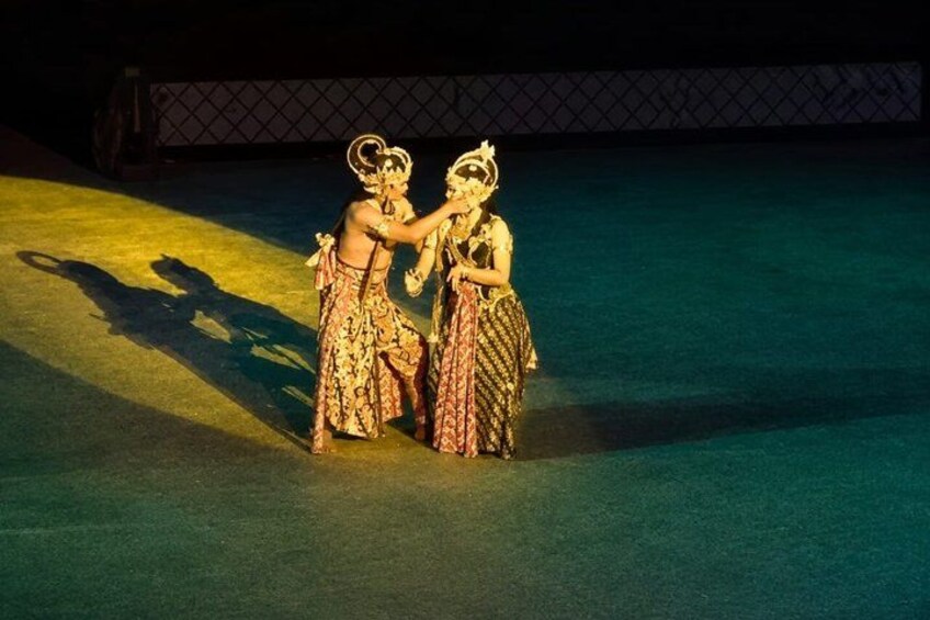 Two performers in traditional costumes on a stage with a spotlight effect. 4