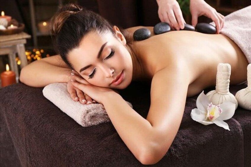 A person receiving a hot stone massage with a towel and a flower on the side. 5