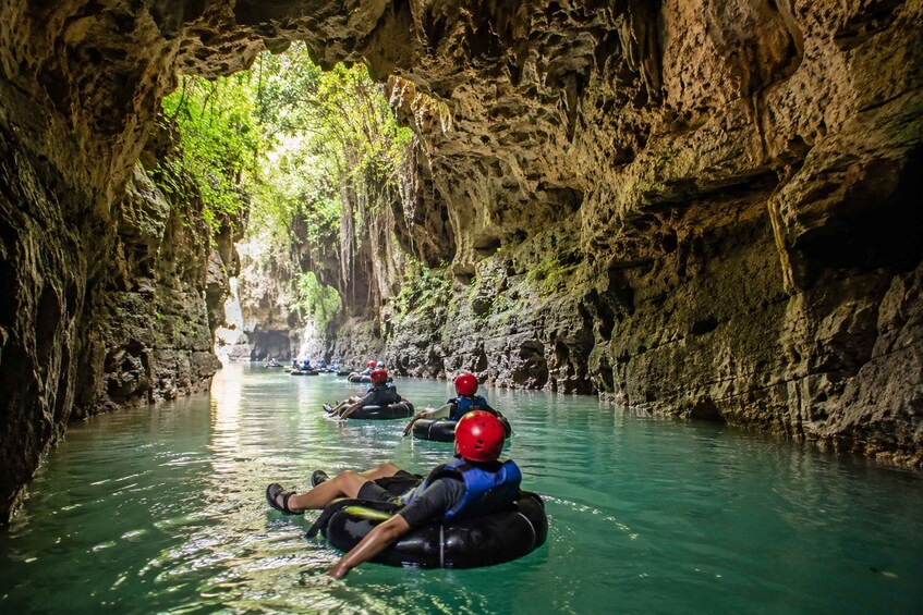 People rafting in a narrow, rocky waterway with natural light filtering through. 5