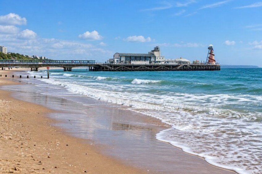 A beach with waves, a pier, and a lighthouse. 3