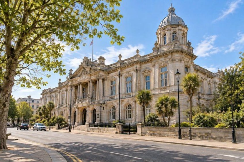 A historic building with a dome and columns, surrounded by trees and a clear sky. 1