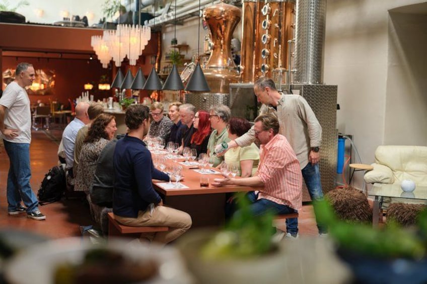 A group of people seated around a table with wine glasses, engaged in conversation. 1