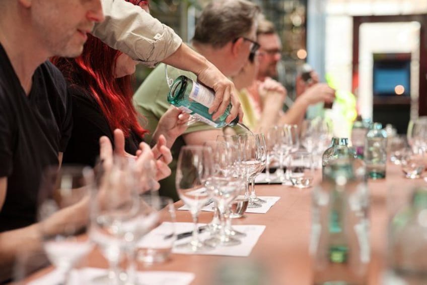 A group of people seated at a table with wine glasses and bottles, likely participating in a wine tasting event. 4