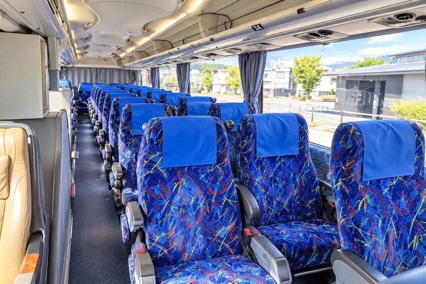 Interior de un tren con asientos de diseño azulado y compartimentos superiores para equipaje. 2