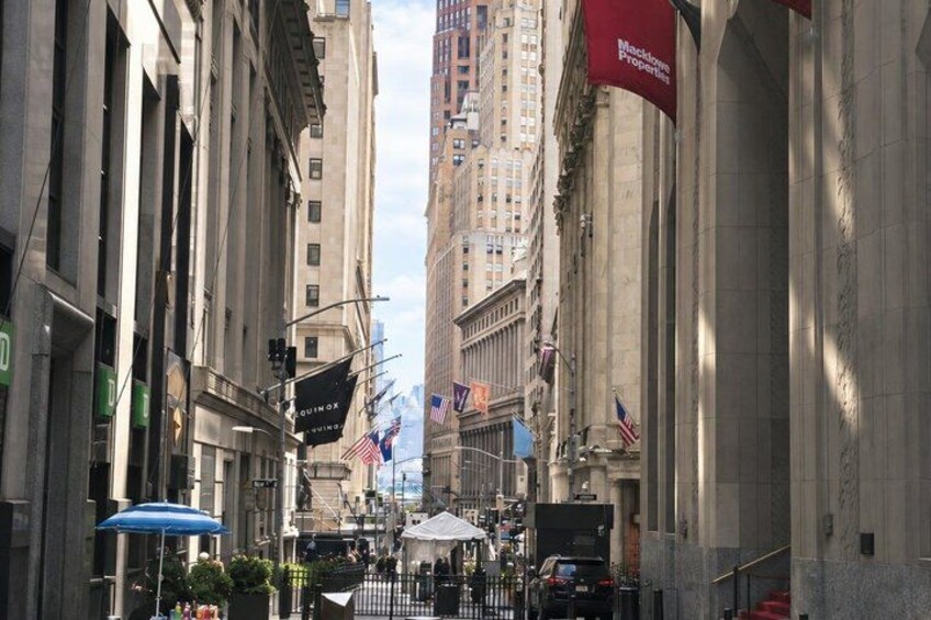 A street with tall buildings, flags, and a red banner. 4